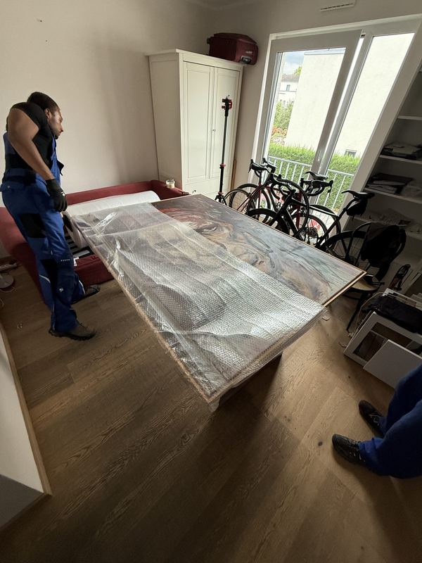 Auf einem Tisch liegt ein großes gerahmtes Bild, komplett in Luftpolsterfolie eingepackt