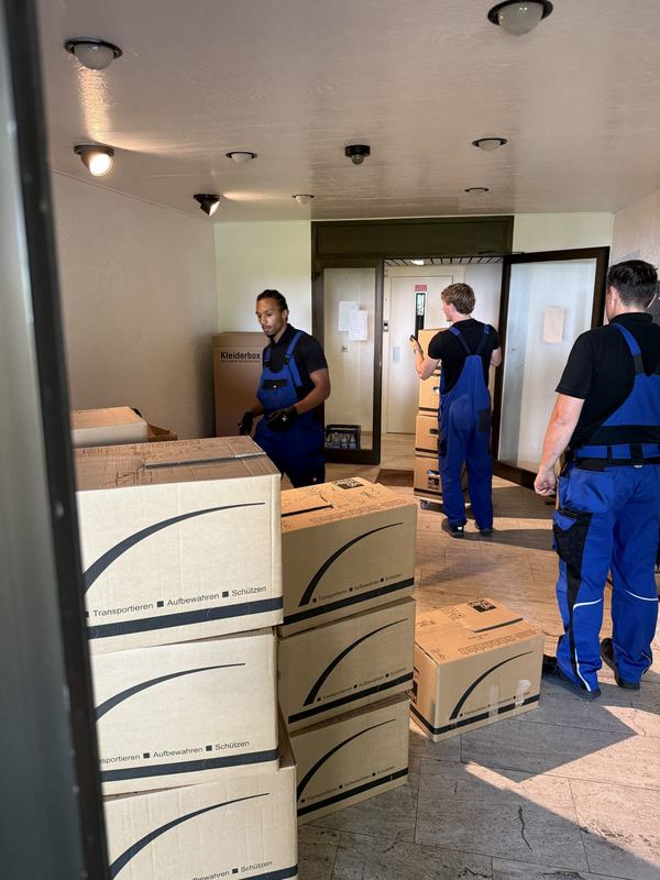 Mehrere Kollegen stellen in einem Flur Umzugskartons zusammen