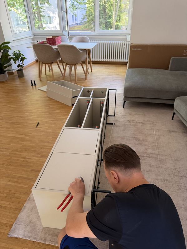 Von oben gesehen arbeitet ein Kollege an einem liegenden Sideboard, dessen Schubladenauszüge offen liegen
