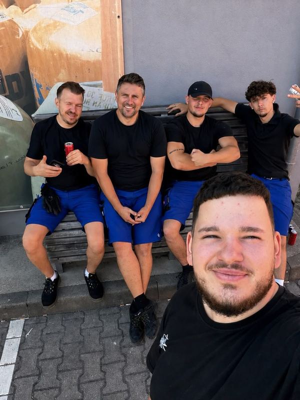 Das Team in Arbeitskleidung macht Pause und sitzt nebeneinander auf einer sonnigen Bank