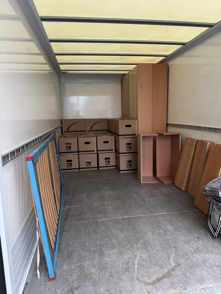 LKW-Laderaum mit Kartons und Klappstühlen, die an der Wand gesichert sind