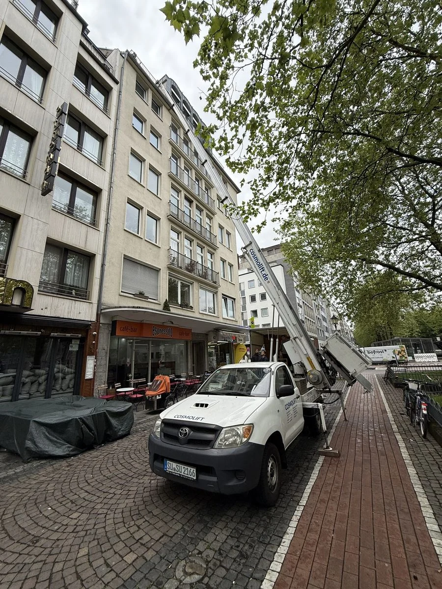 Der ausgefahrene Mast des Möbellifts ragt über eine Baumallee hinaus