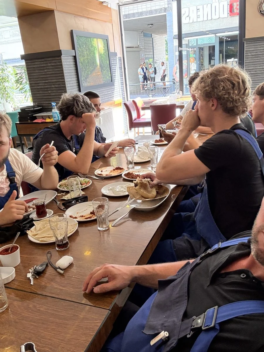 Das Team sitzt in der Pause zusammen am Tisch und isst gemeinsam