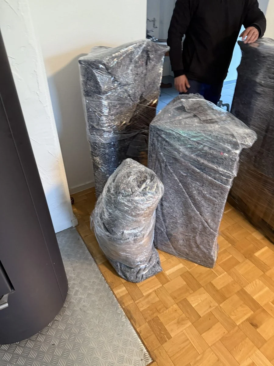 Ein Kollege steht mit dem Rücken zur Kamera neben verpackten Gegenständen am Kamin