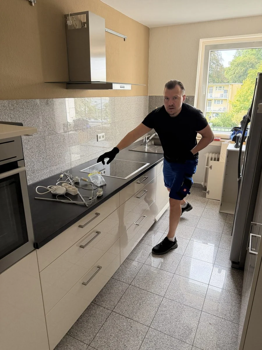 Ein Kollege beugt sich bei der Montage zu einem Küchenunterschrank und richtet ihn aus