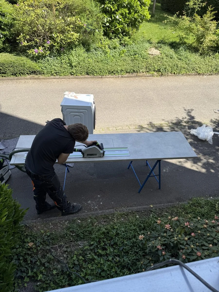 Ein Umzugshelfer schiebt eine Sackkarre mit einer Kiste über die Straße zum Fahrzeug